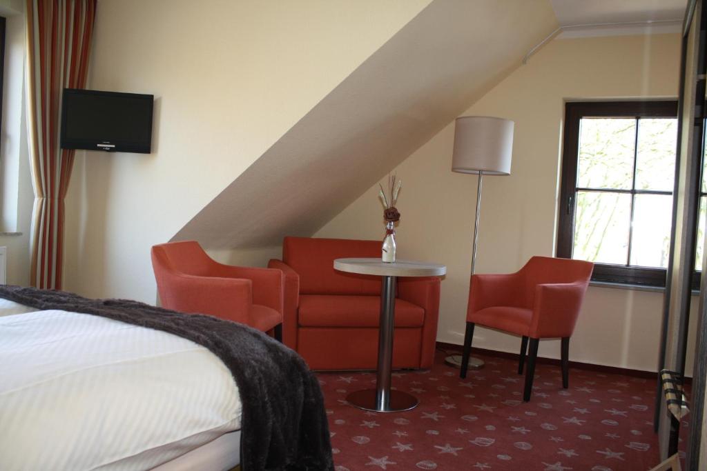 グレートジールにあるHotel Zum Alten Sielのベッド、テーブル、椅子が備わるホテルルームです。