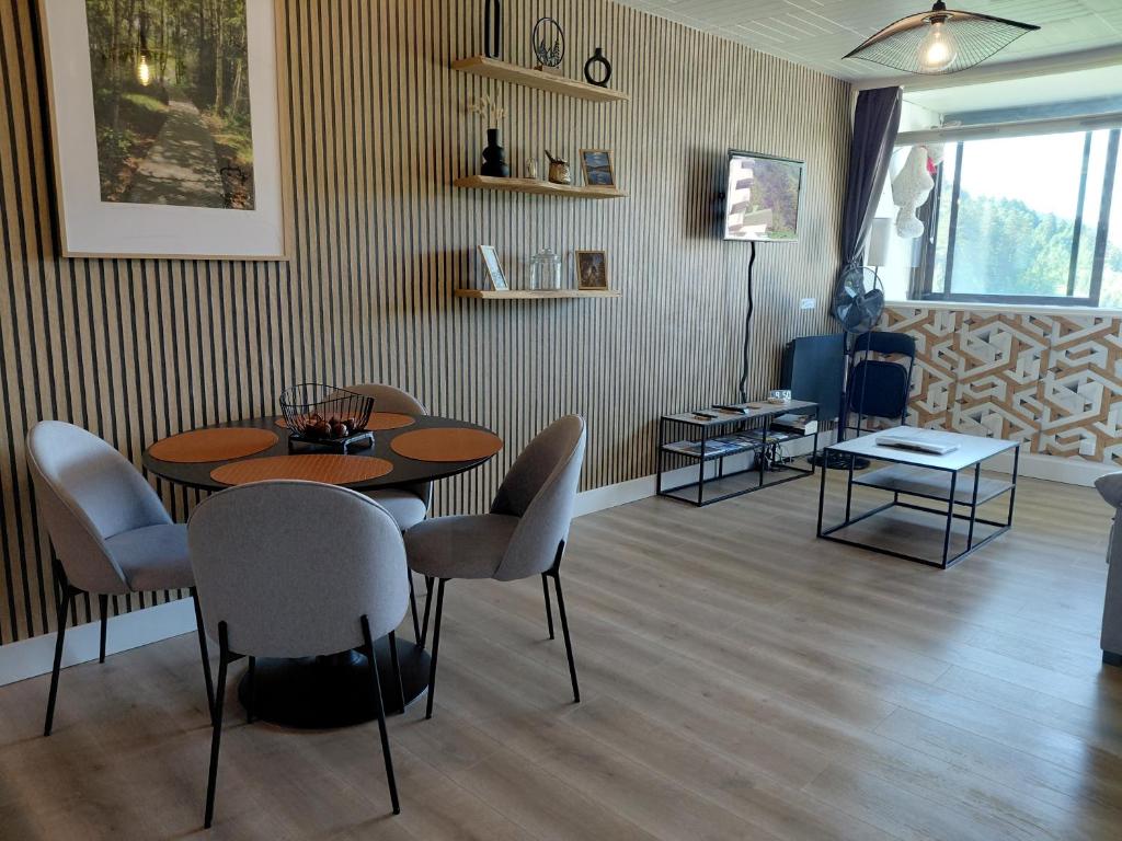 a room with a table and chairs and a television at Le 408 des pistes in La Bresse