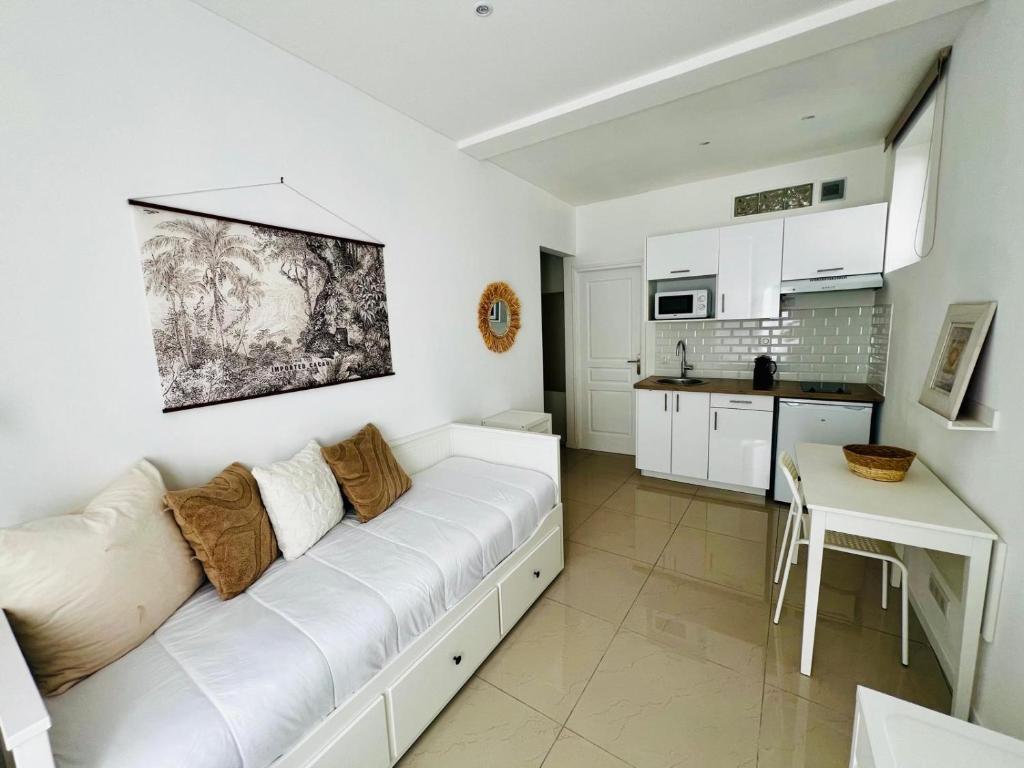 a living room with a white couch and a kitchen at Chic & Cosy in Antibes