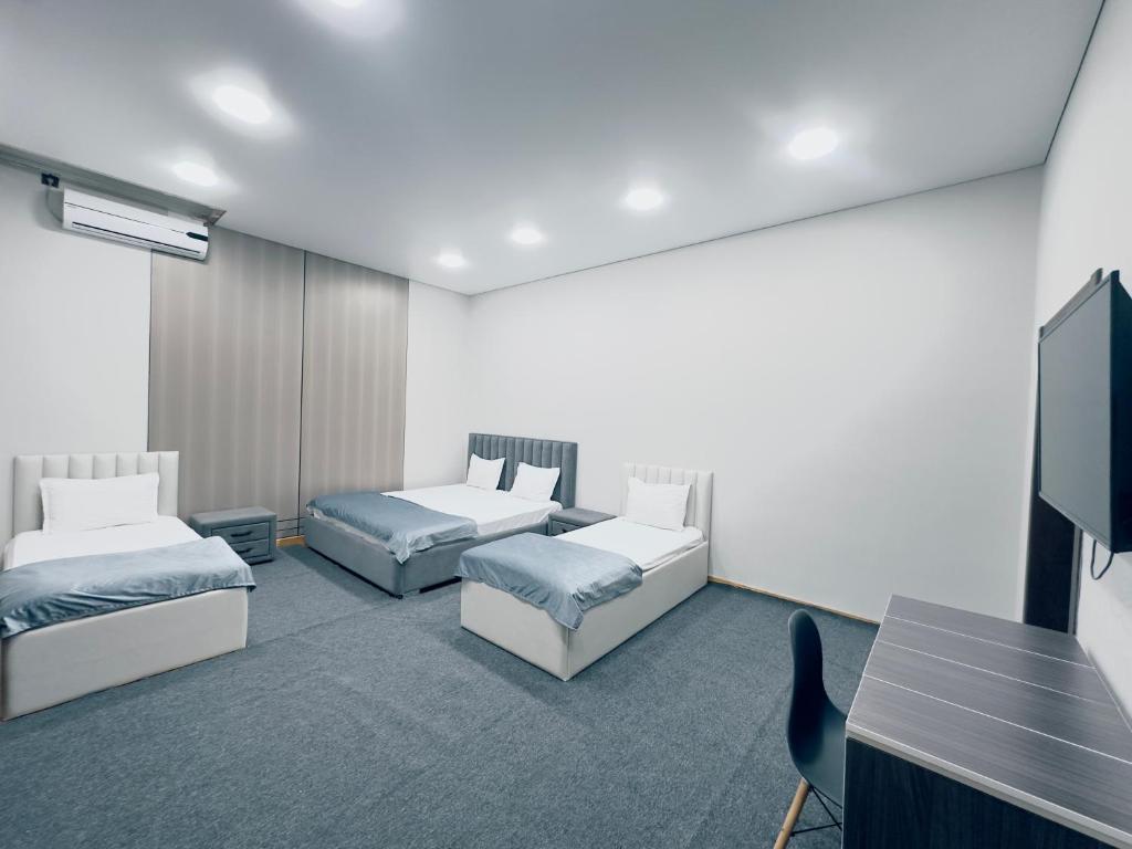 a room with two beds and a flat screen tv at Center Hotel Darhan in Tashkent