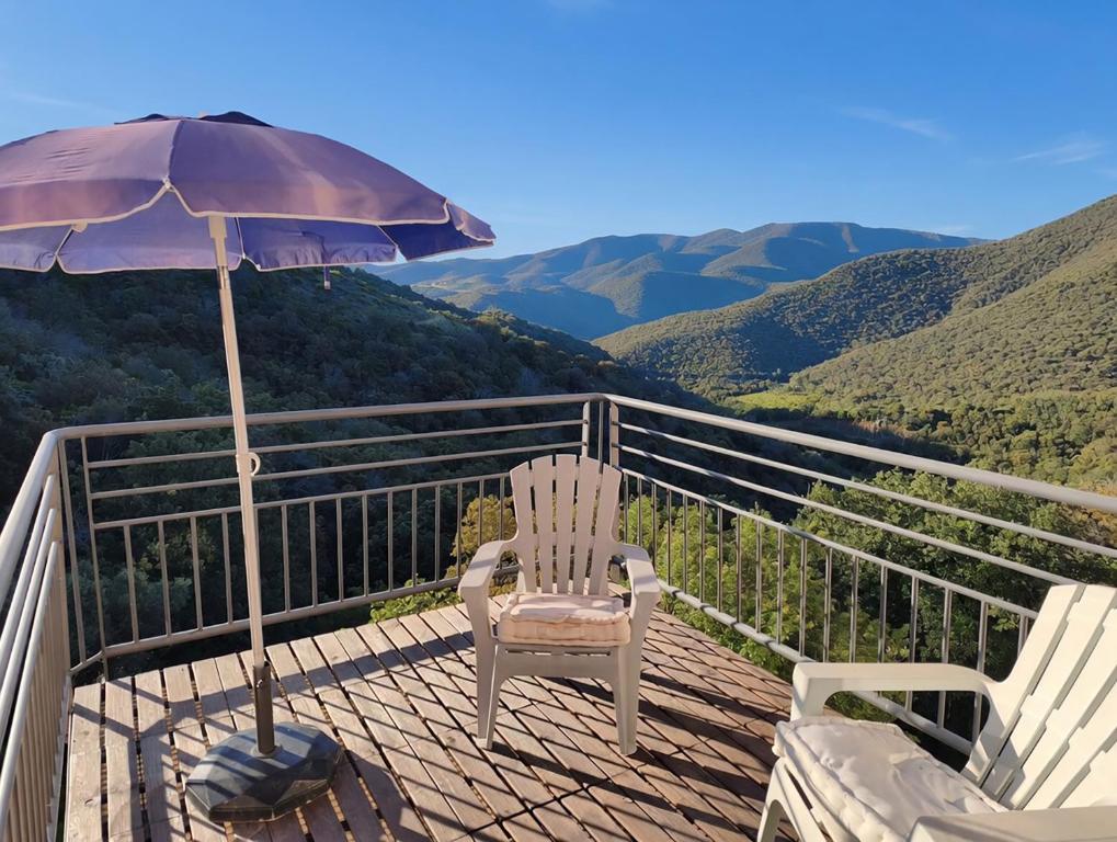 a chair and an umbrella on a deck with a view at Pyrénées Mon Amour in Felluns