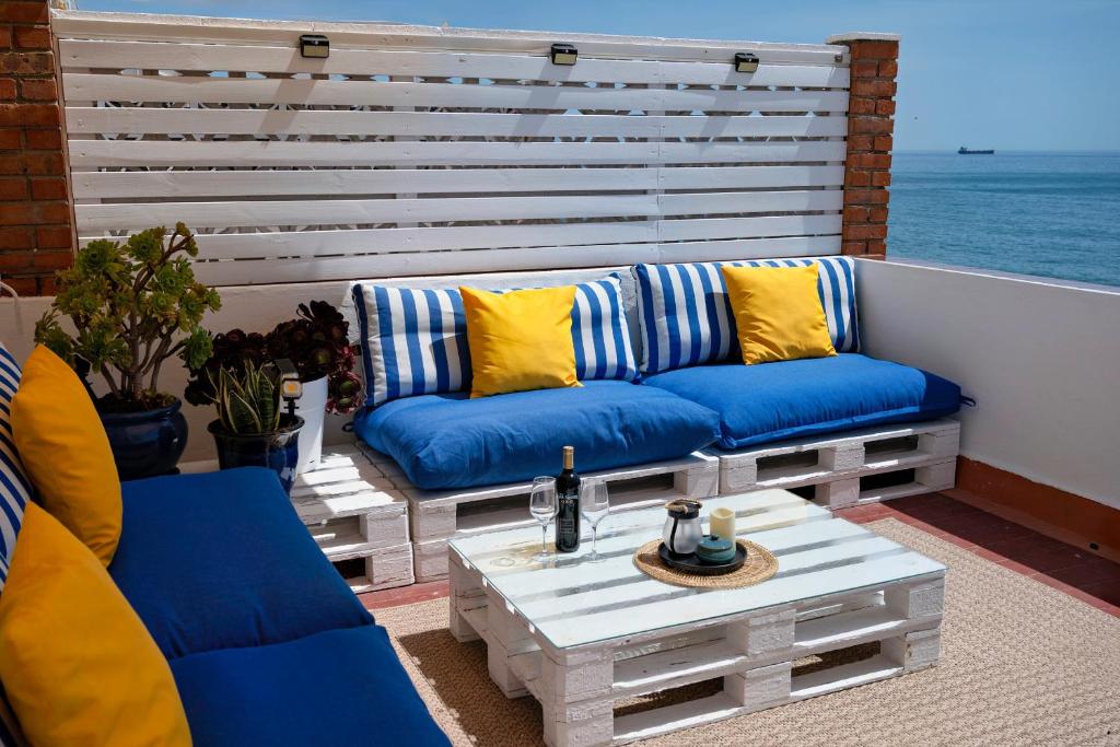 a patio with two blue couches and a coffee table at Beachfront Apartment - 2 Terraces - Stunning Sunrises in Gibraltar