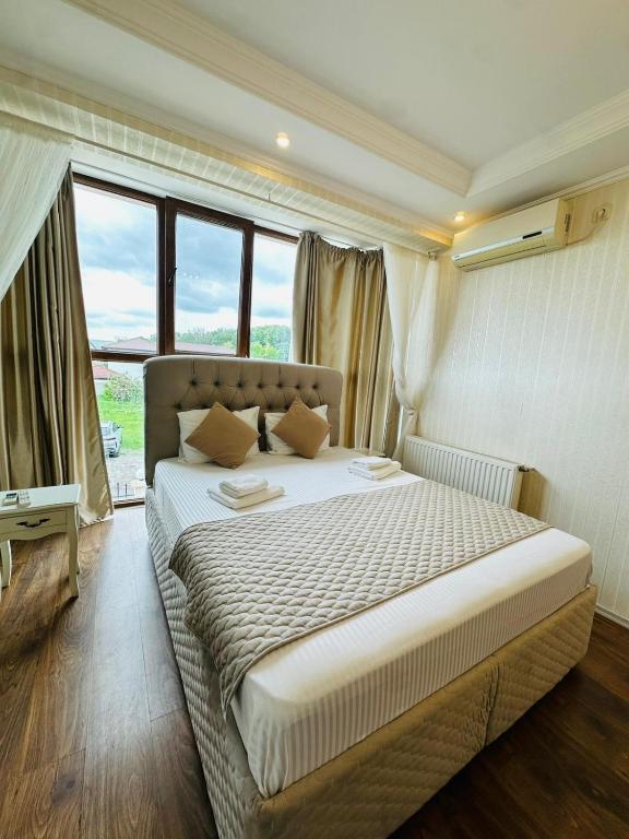 a bedroom with a large bed in a room with windows at Ami Residence Bucharest Airport,Therme&FREE PARKING Otopeni in Otopeni