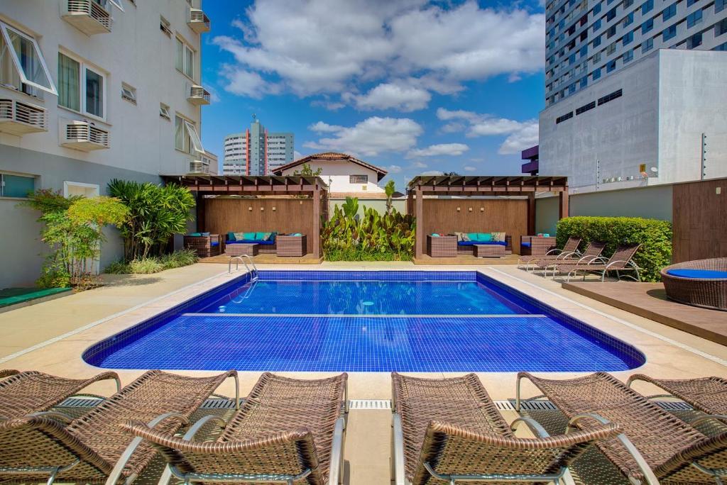 a swimming pool with chairs and a building at GoldMen Business Joinville in Joinville