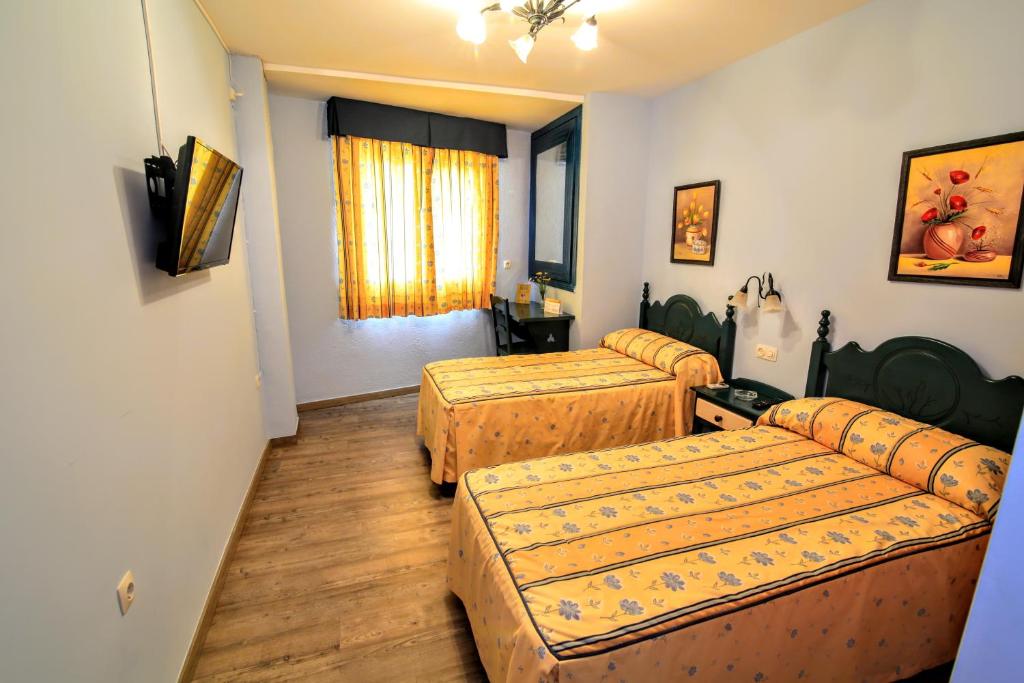 a hotel room with two beds and a window at Pension Rural La Fonda in Dúrcal