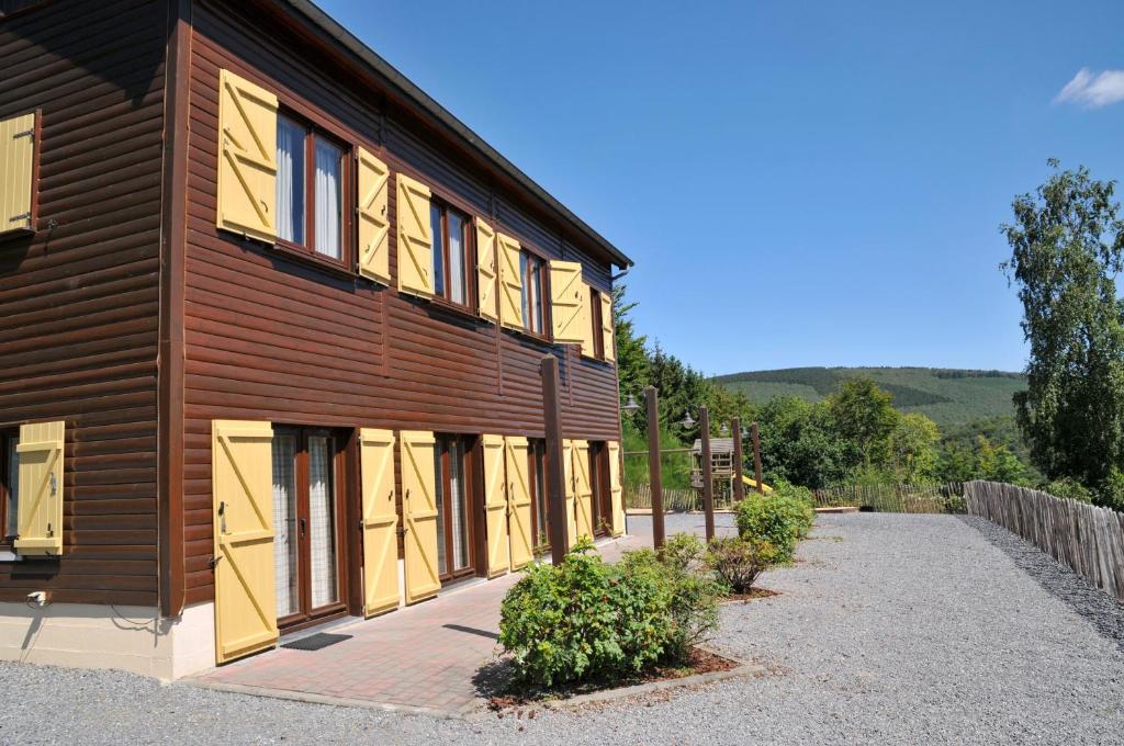 a wooden building with yellow shutters on it at Les Rochettes - Jupiter in La-Roche-en-Ardenne