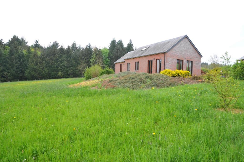 un piccolo edificio rosso in un campo di erba verde di Laloux a Laloux