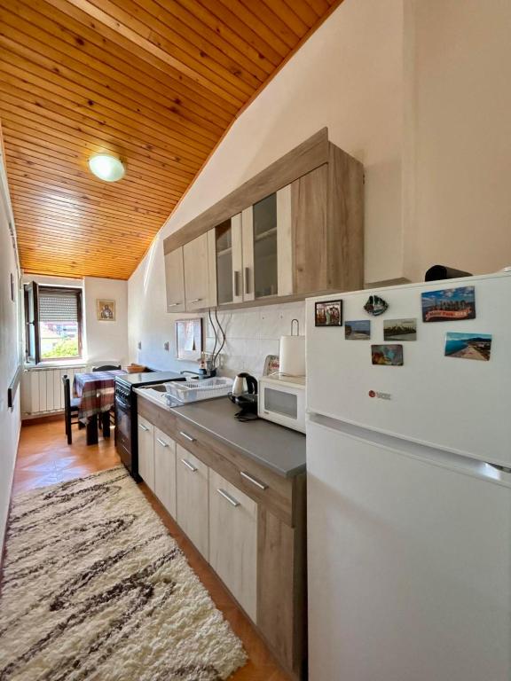 a kitchen with a white refrigerator and a wooden ceiling at Apartman Stankovic in Pirot