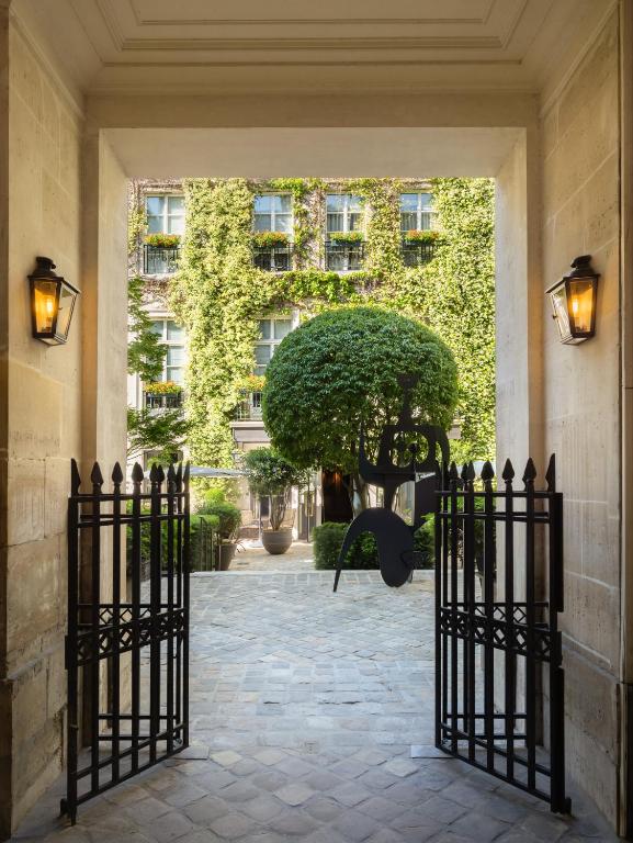 a gate leading into a building with a bush at Le Pavillon de la Reine & Spa, Place des Vosges in Paris