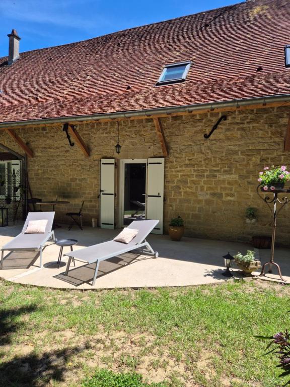 a patio with two lounge chairs and a building at A La Maison in Les Repôts