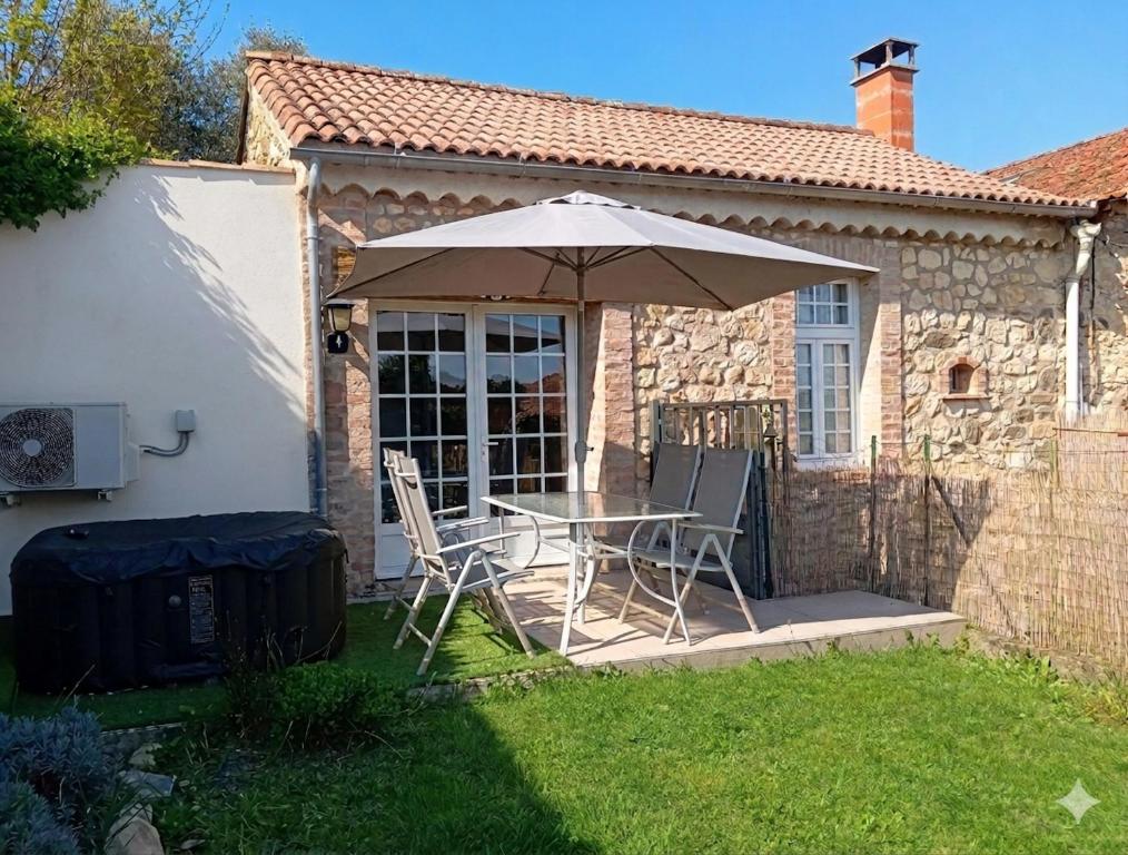 a table and chairs under an umbrella in a yard at Maisonnette en pierre in Saint-Victor-de-Malcap
