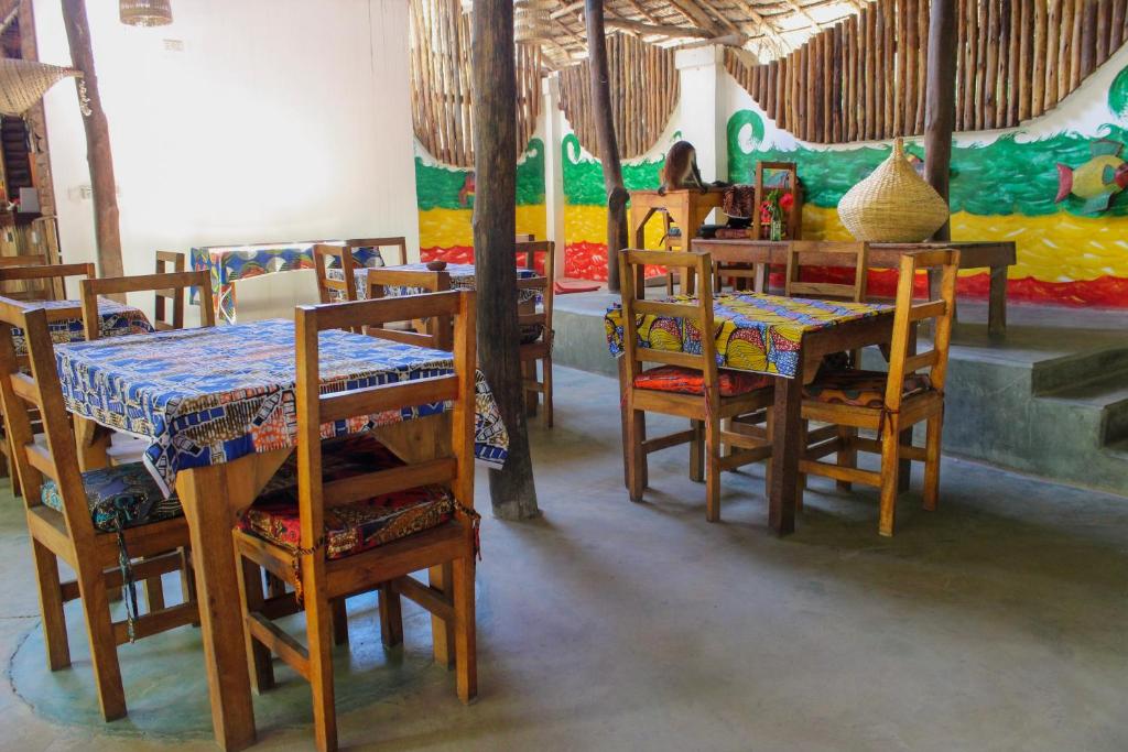 a dining room with tables and chairs and a painting at Sagando Bungalow in Michamvi