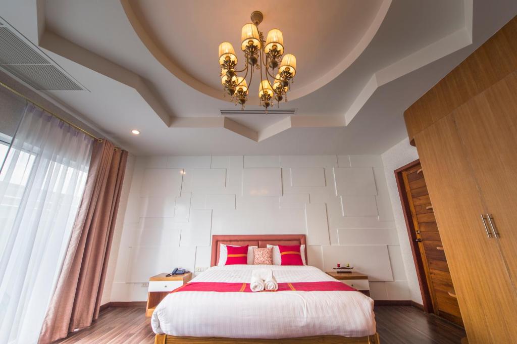 a bedroom with a large bed and a chandelier at The Canal Ratchaburi in Ratchaburi