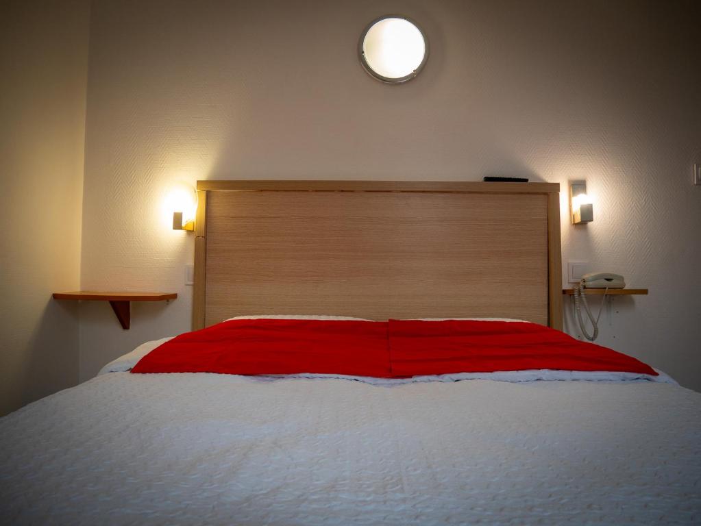 a bedroom with a large bed with a red blanket at Hotel BETHEL in Nevers