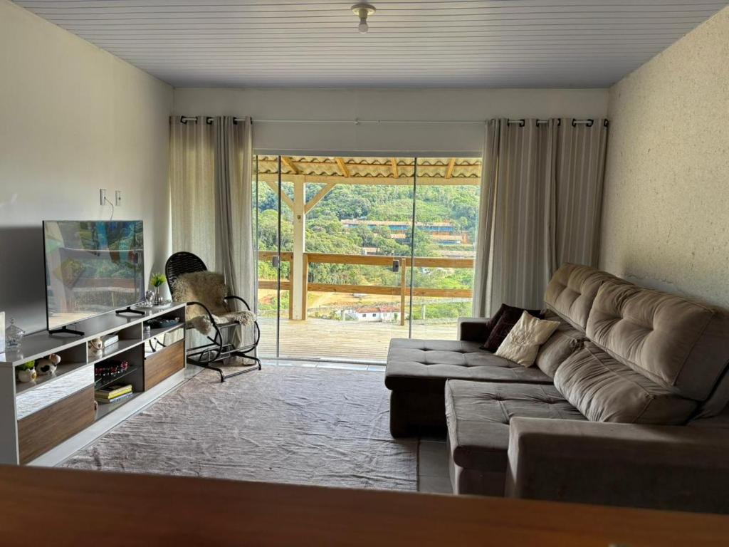 a living room with a couch and a large window at Sitio em São Pedro de Alcantara in São Pedro de Alcântara