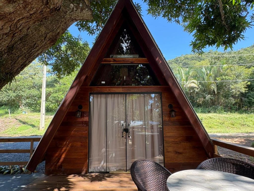 a house with a triangular roof with a glass door at Complexo Turístico Canaã in Nobres