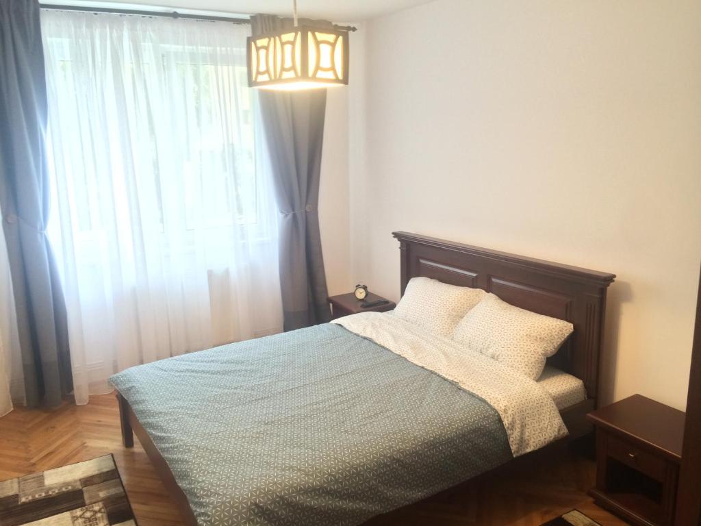 a bedroom with a bed with a chandelier and a window at Apartment KronDays in Braşov