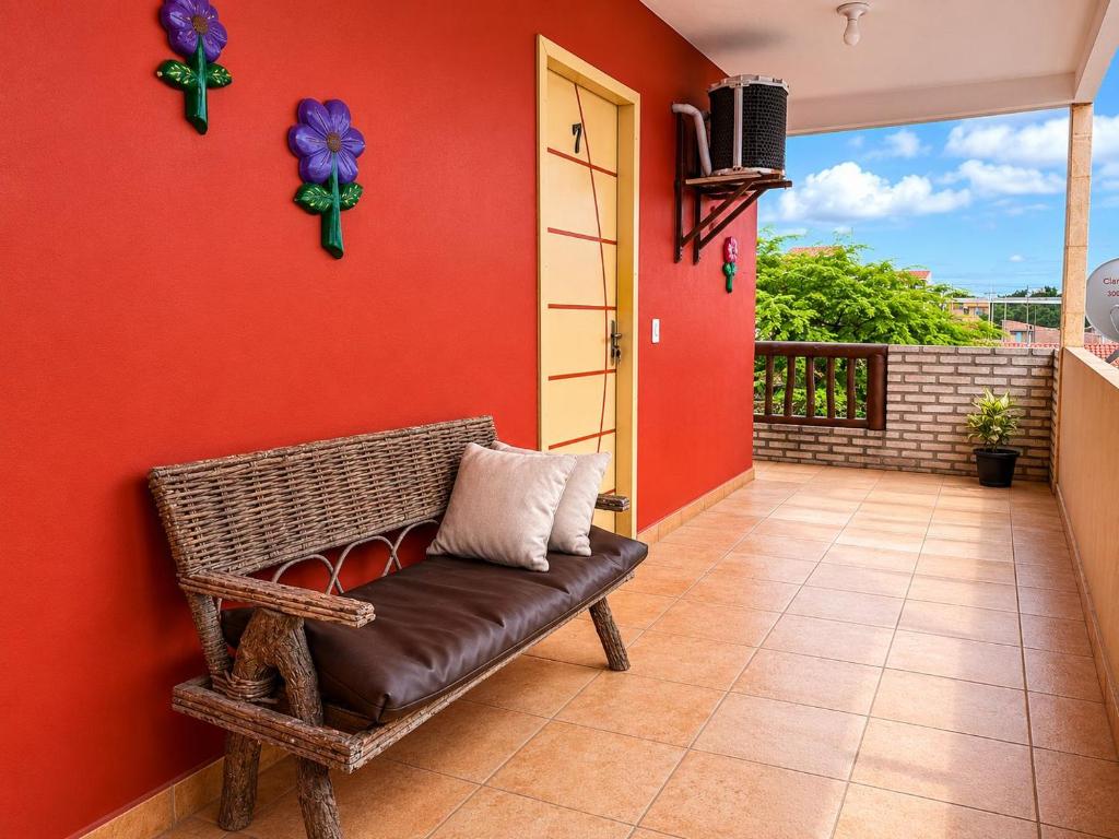 a bench in a room with a red wall at Pousada Wilclé Center Preá in Prea