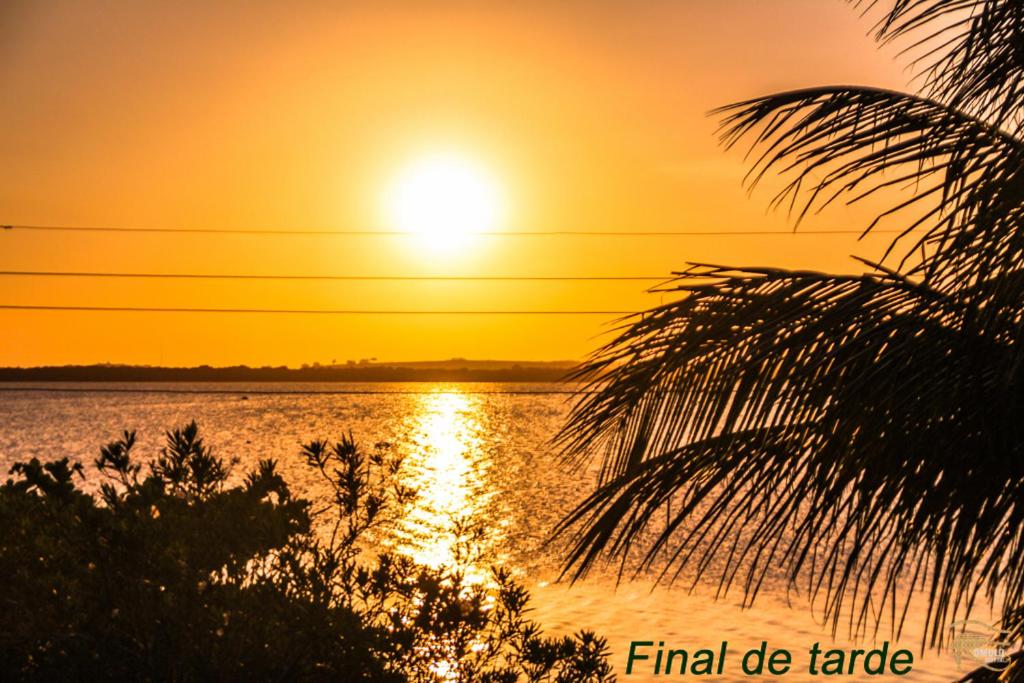 a sunset over a body of water with a palm tree at Casa de temporada em Araruama in Araruama