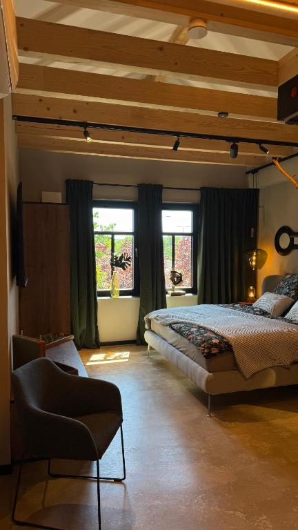 a bedroom with two beds and a chair and windows at Gleisbett 12-2 in Meiningen
