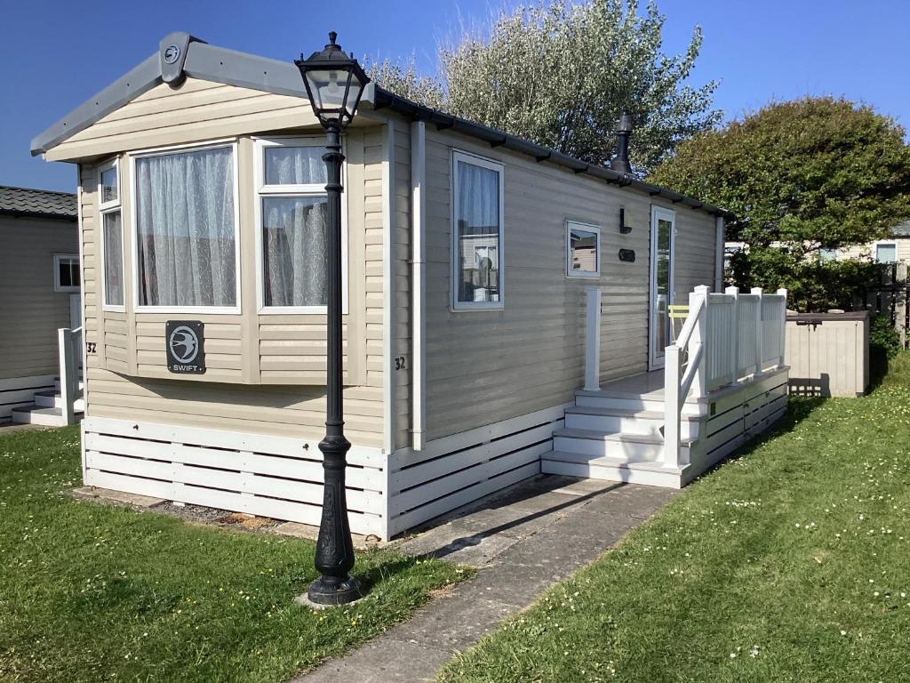a small house with a light pole in front of it at Cosy Costal Escape in Westward Ho