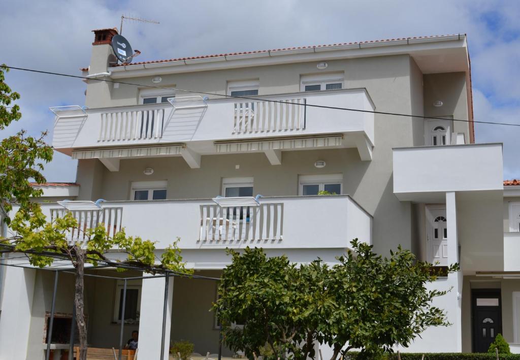 un immeuble avec des balcons blancs et des arbres dans l'établissement Apartments Pineta Franko, à Fažana