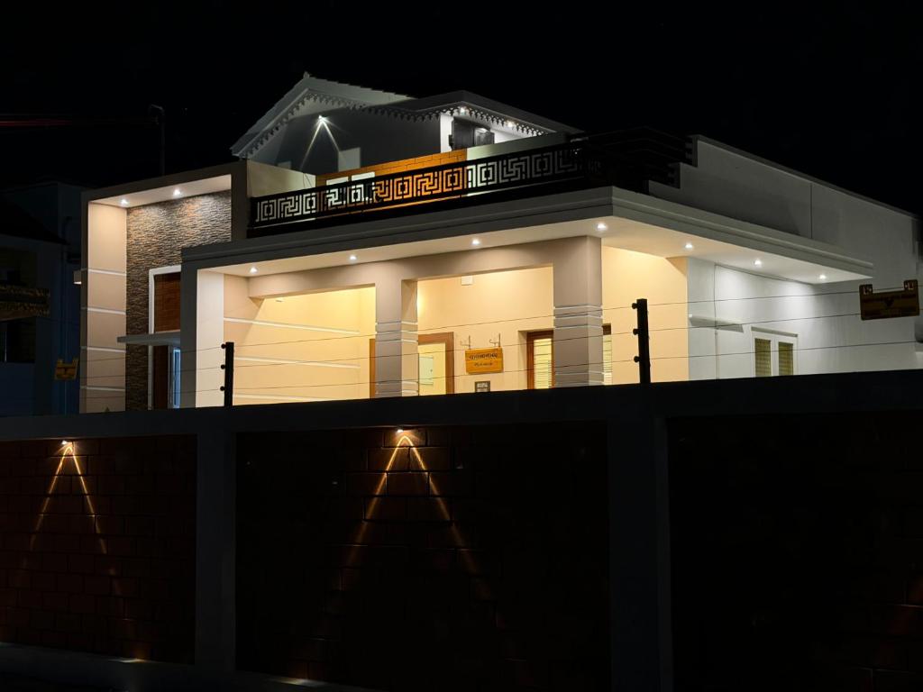 a white building with a sign on it at night at Vihaalaya stays in Tozhuppedu
