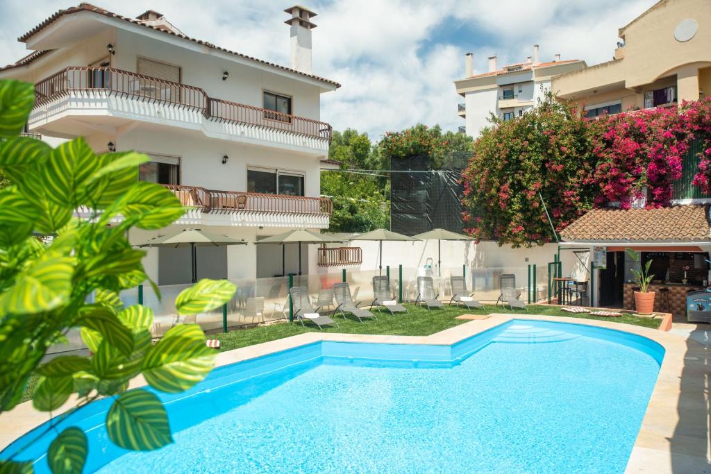 a villa with a swimming pool in front of a building at Estoril Guest Palace in Estoril