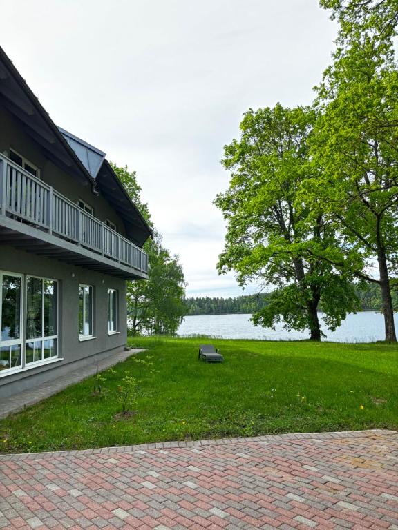 a house with a grassy yard next to a lake at Orinoko Guest House in Stacija Sece