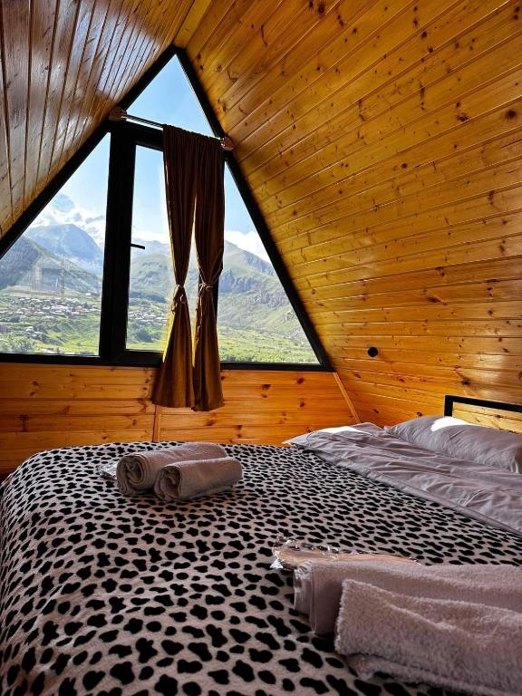 a bed in a room with a large window at Alagi Cottage Kazbegi in Kazbegi
