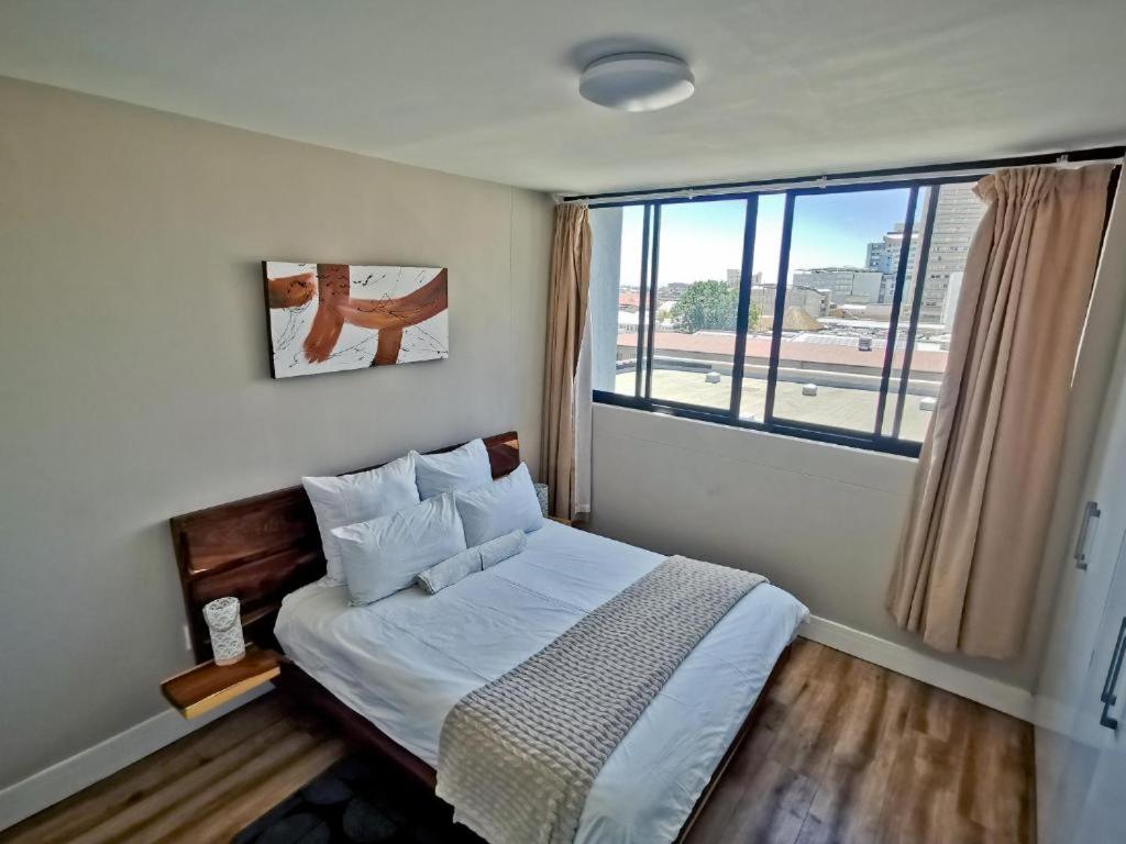 a bedroom with a bed with a large window at The Safari Launchpad Windhoek in Windhoek