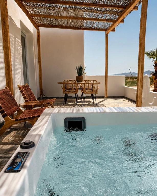 a hot tub in a patio with a table and chairs at Kyma Sunset Suite w Prvate Jacuzzi in Paros National Airport