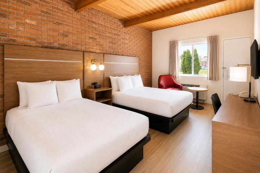 a hotel room with two beds and a desk at Ramada by Wyndham 1000 Islands Gananoque in Gananoque