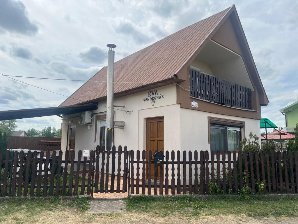 a small white house with a wooden fence at Éva Vendégház in Hajdúnánás