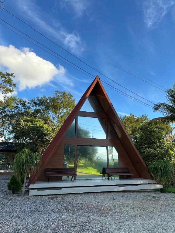 a triangular house with two benches in a park at Chalé A-Frame em Garanhuns - PE/ Rota do Frio in Garanhuns
