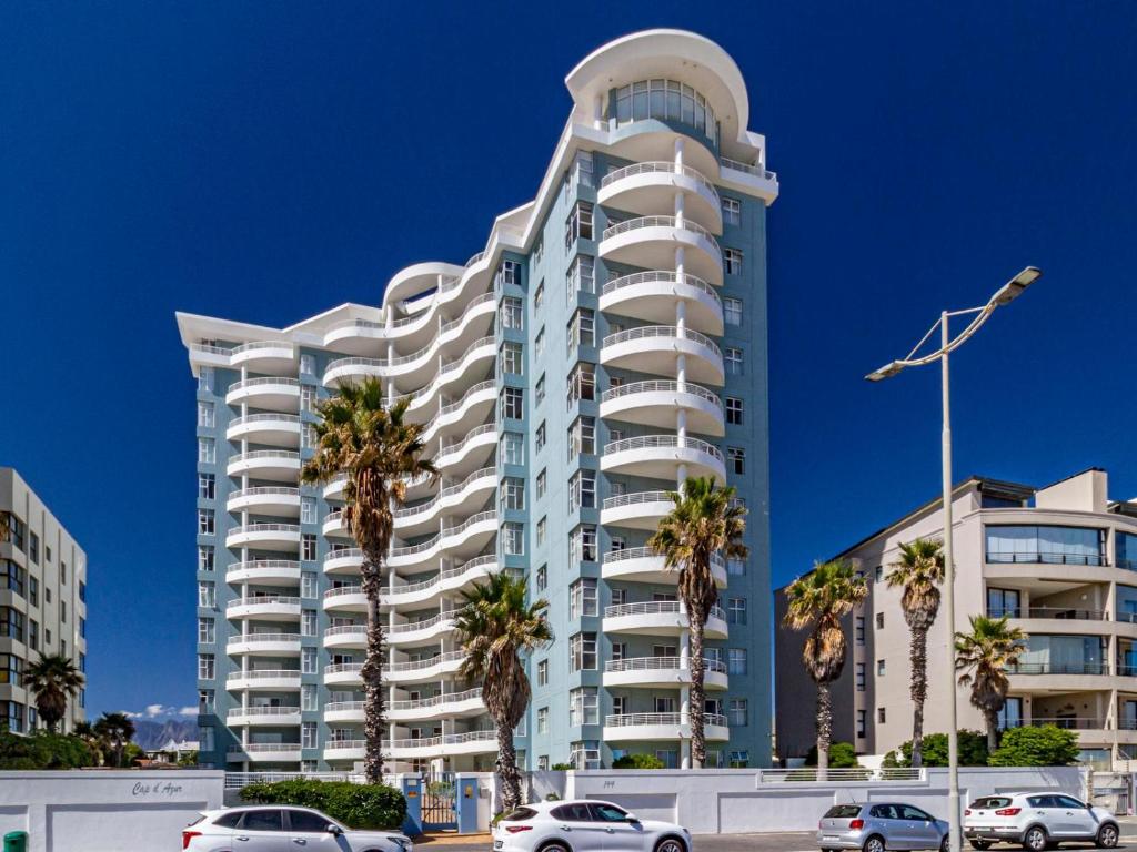 a tall white building with palm trees in front of it at 75 Cap D'Azur in Strand