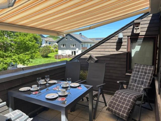 a table and chairs on a patio with a roof at Ferienwohnung Kölbel Familienurlaub in der Natur in Schmallenberg