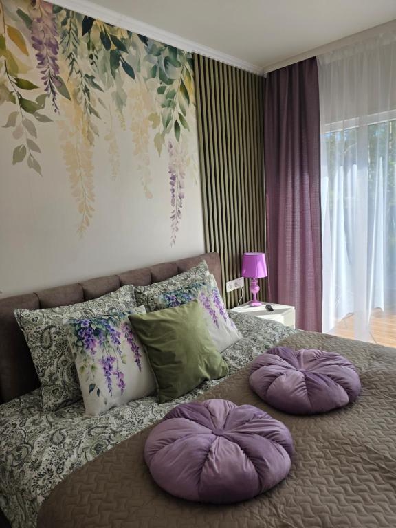 a bedroom with a bed with purple pillows on it at APARTAMENTI BrivdienuKolka in Kolka