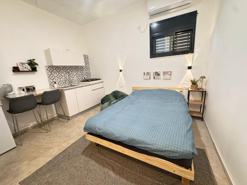 a bedroom with a bed and a small kitchen at קסם צפתי- סטודיו in Safed
