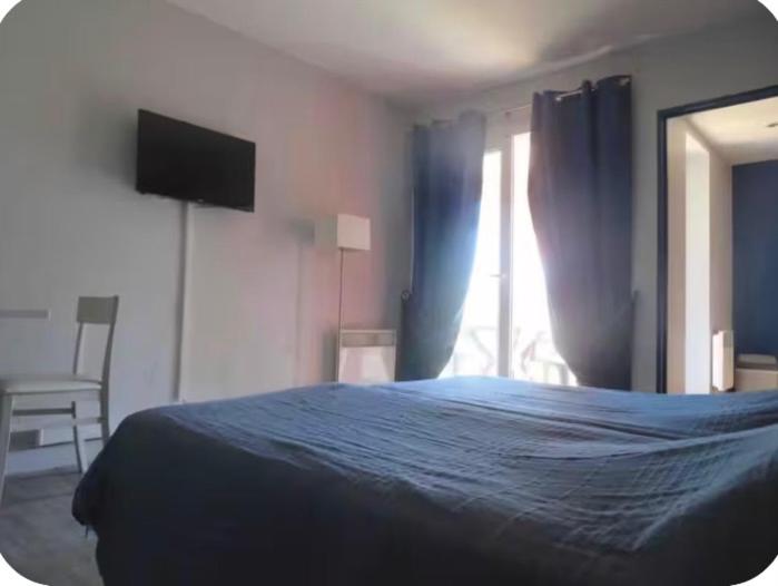 a bedroom with a blue bed and a window at Studio village 9 in Arles