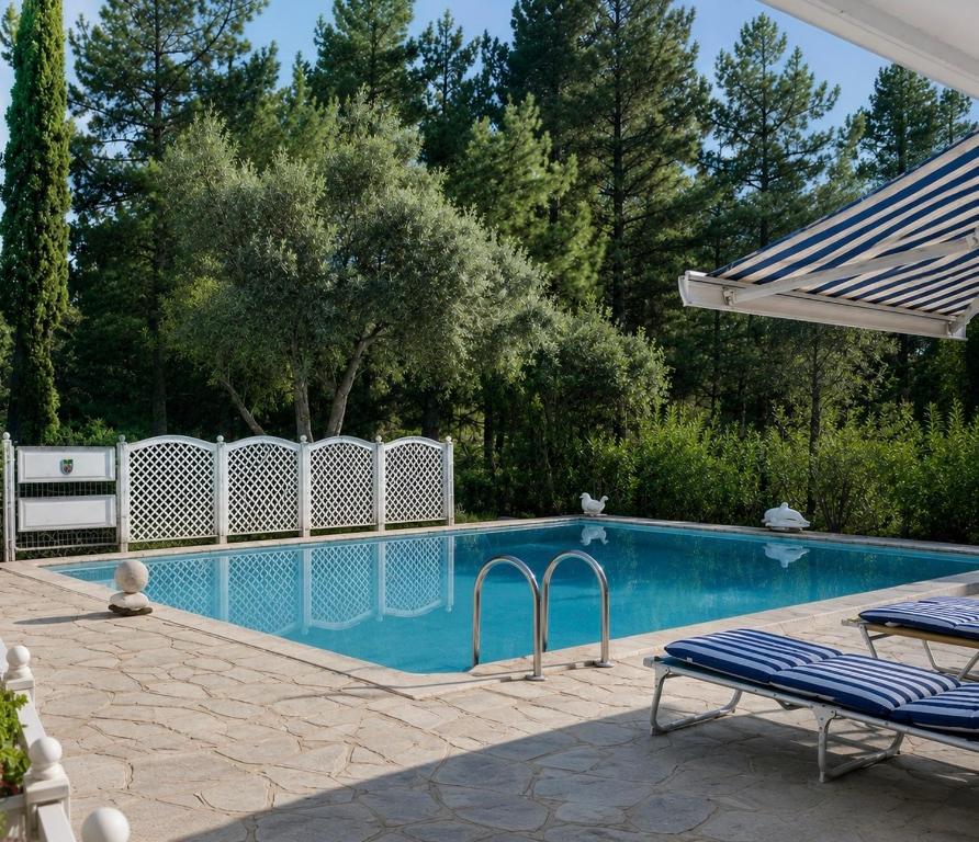 a swimming pool with a fence and two lounge chairs at Villa Marlene in Astris