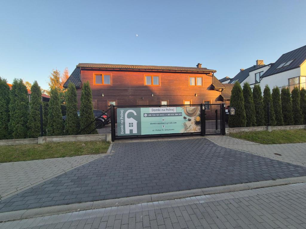 a gate with a sign in front of a house at Domki na Polnej in Grzybowo