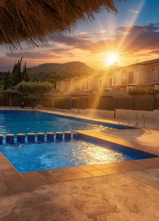 a swimming pool with a sunset in the background at Kalma House in Torroella de Montgrí