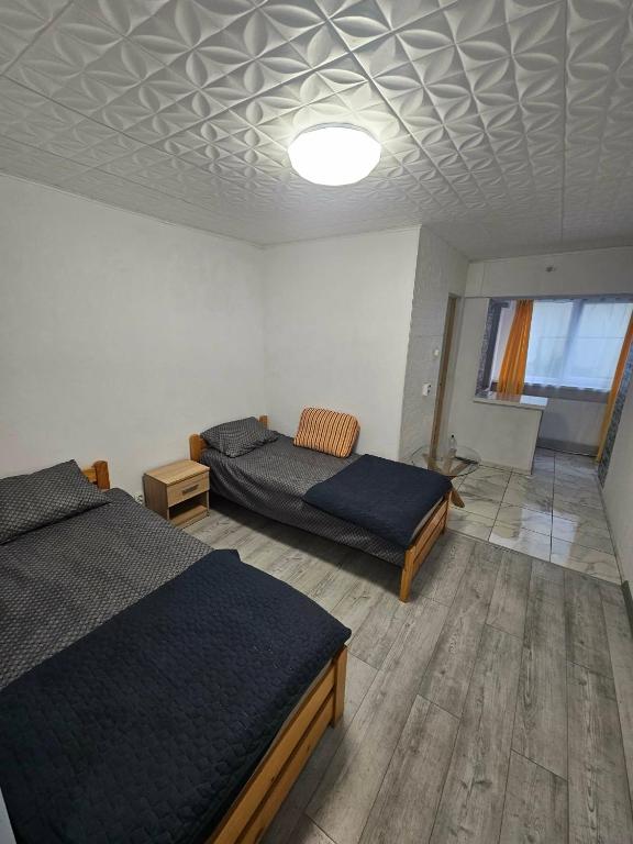 a bedroom with two beds and a ceiling at BOMBA Apart in Târgu Secuiesc
