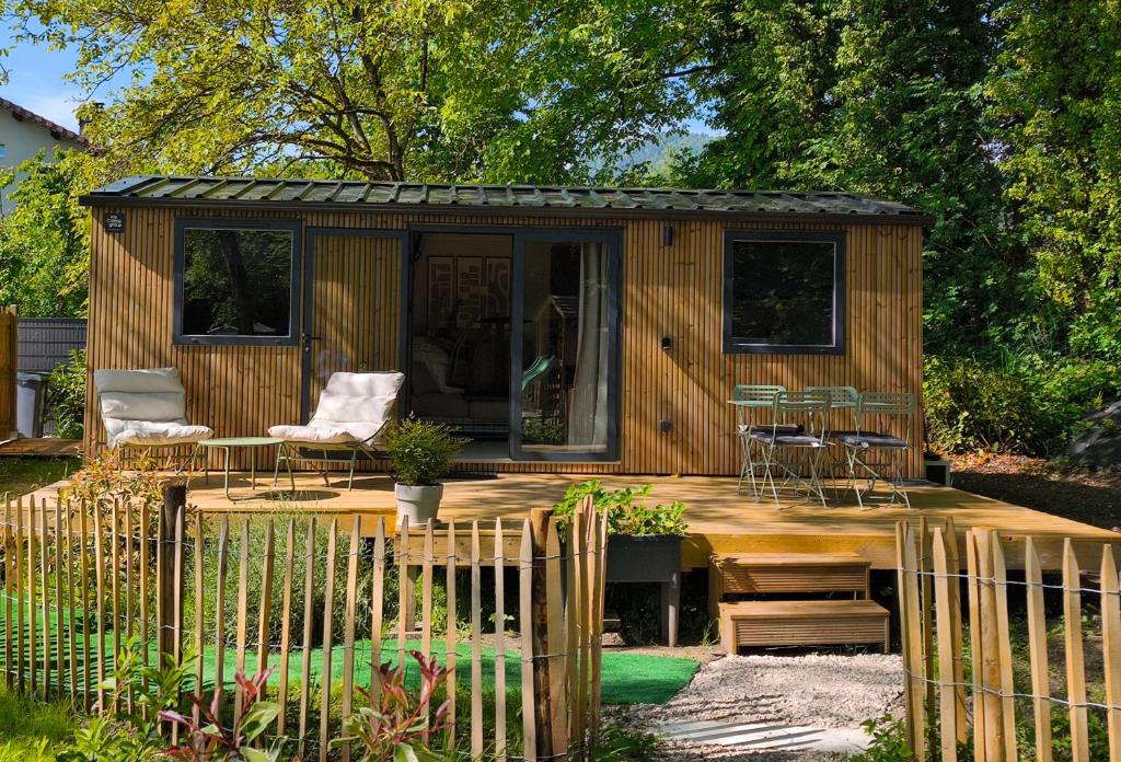 a wooden cabin with a table and chairs in a garden at Tiny House ALPEA in Fillinges