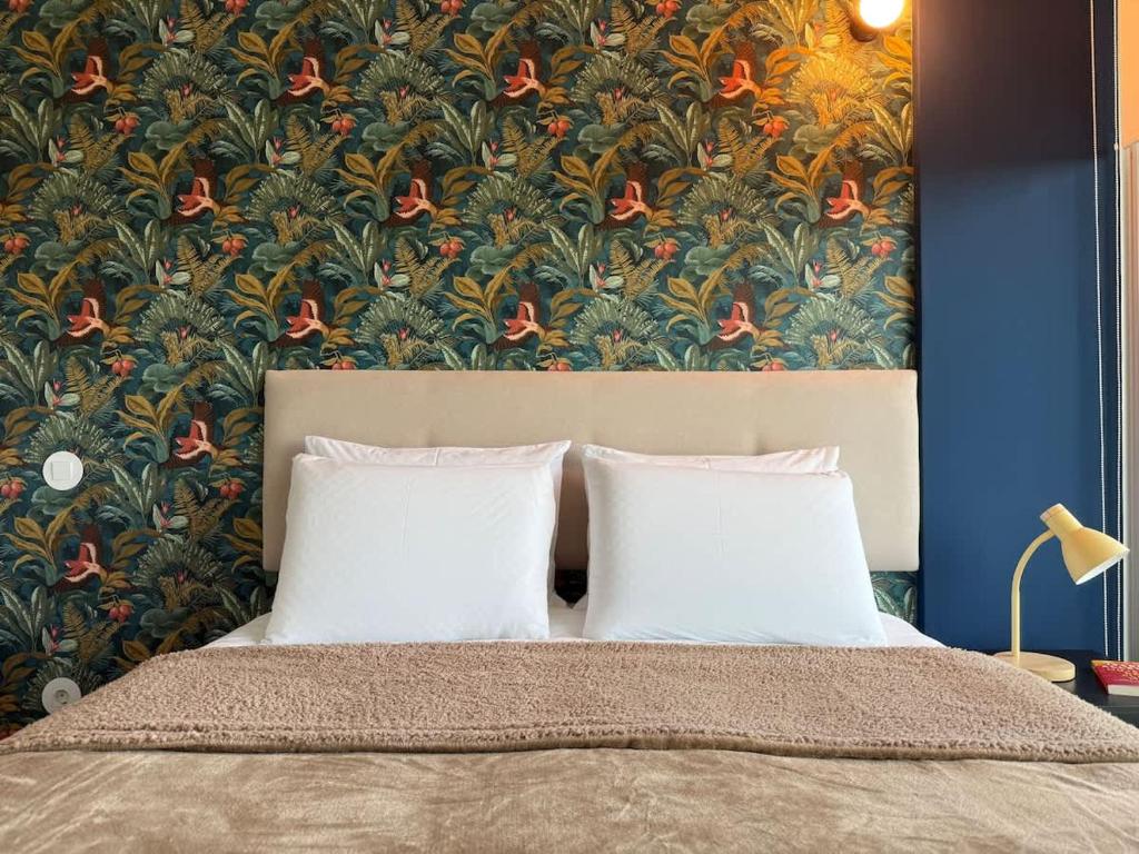 a bed with two pillows in front of a floral wallpaper at Na Outra Margem - Douro River Views - Free Parking in Vila Nova de Gaia