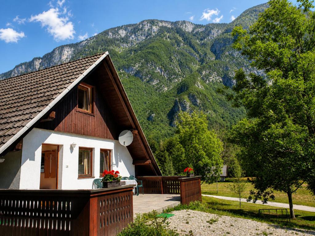 a house with a deck and mountains in the background at Bohinj Star Apartments in Bohinj