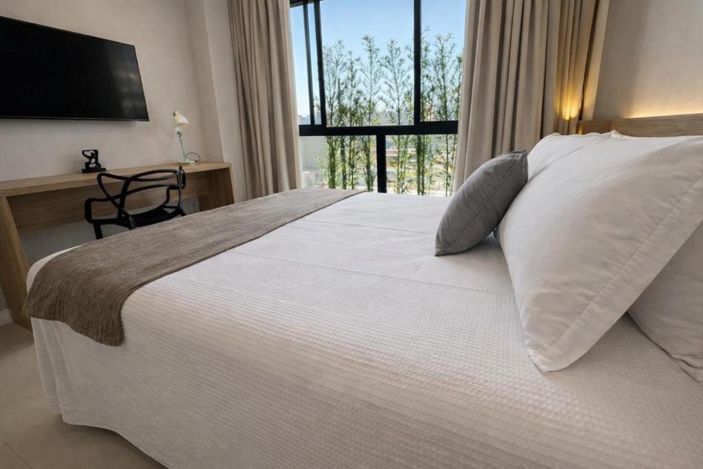 a bedroom with a large white bed with a window at Apartamento prox a Arena Niteroi, Uff e Barcas in Niterói