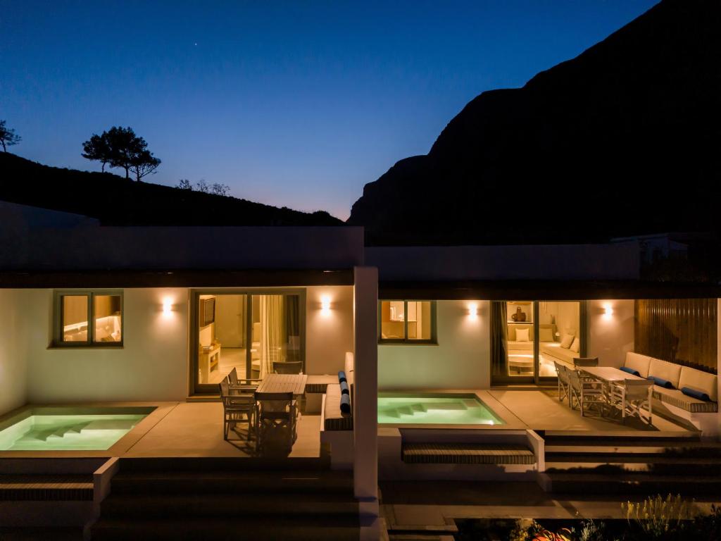 a house with a patio and a swimming pool at night at Pefki Luxury Suites in Telendos