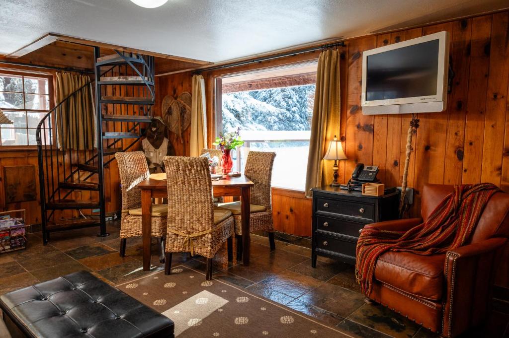 a living room with a table and chairs and a television at Riverview Cabin at O-Bar-O in Durango
